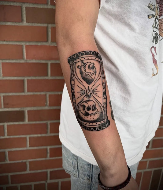 Medium Black and Grey Hourglass with Heart and Skull Tattoo on Women Arm by @_darkritual