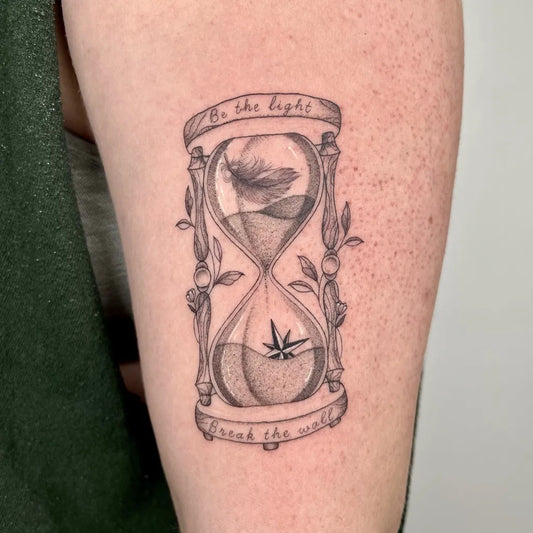 Medium Black and Grey Hourglass with Marijuana Leaf Tattoo on Men Arm by @amazinkgraceartistry