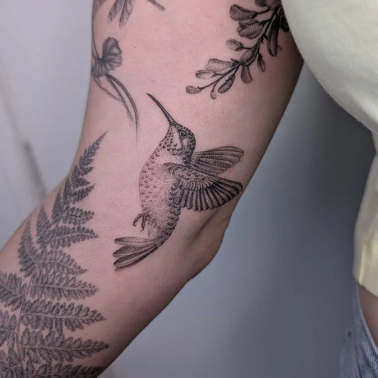 Medium Black and Grey Hummingbird with Ferns and Flowers on Women Arm Tattoo by @die_monde