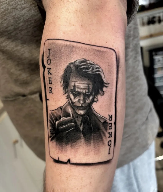 Medium Black and Grey Joker Card on Men Arm Tattoo by @johnbyrnetattoos