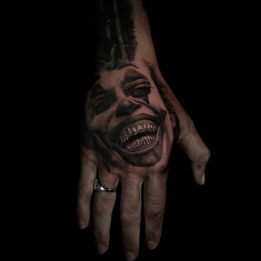 Medium Black and Grey Joker Face on Men Hand Tattoo by @sebotis