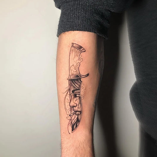 Medium Black and Grey Knife with Face Tattoo on Men Arm by @tattoerr.arif