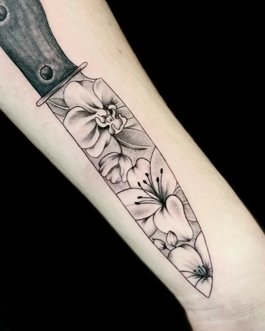 Medium Black and Grey Knife with Lilies Tattoo on Women Arm by @red_apple_tattoo