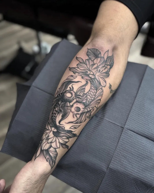 Medium Black and Grey Koi and Lotus Tattoo on Men Arm by @blacklinetattoos_sa