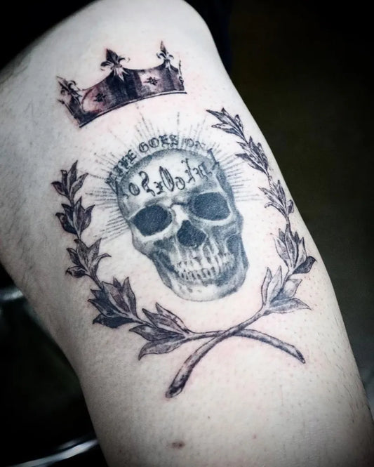 Medium Black and Grey Laurel Wreath Crowned Skull Tattoo on Men Arm by @j.ryong__tattoo