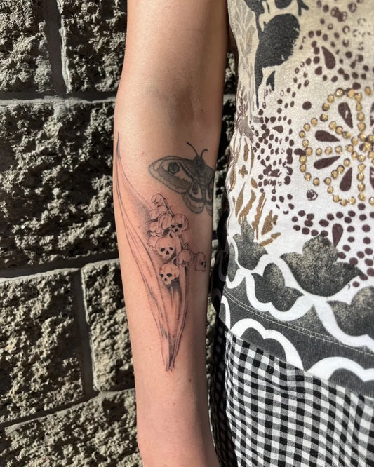 Medium Black and Grey Lily of the Valley and Moth on Women Arm Tattoo by @emeraldbeetattoo