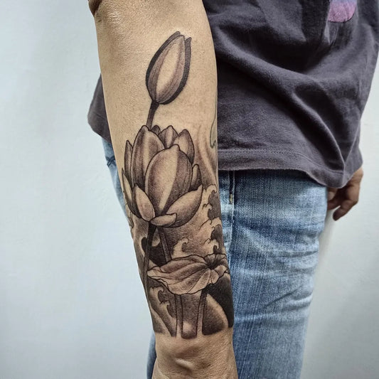 Medium Black and Grey Lotus Flower with Leaves on Women Arm Tattoo by @jeffchewtattoostudio