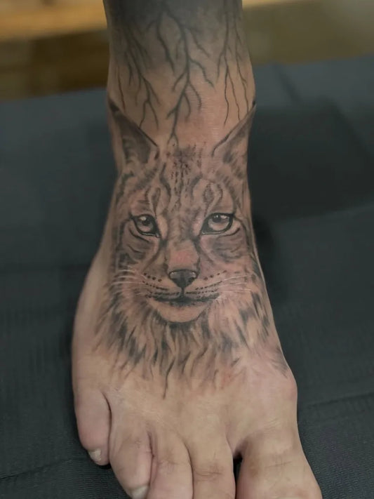 Medium Black and Grey Lynx Face Tattoo on Men Foot by @dieschulz_tattoo