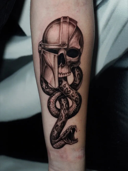 Medium Black and Grey Mandalorian Helmet Skull and Snake Tattoo on Men Arm by @tattoo_farbgefuehl