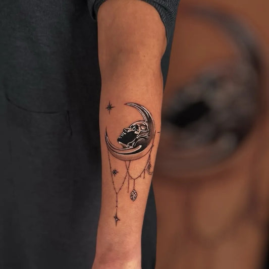Medium Black and Grey Moon Skull Charm Tattoo on Women Arm by @inkgallerynj