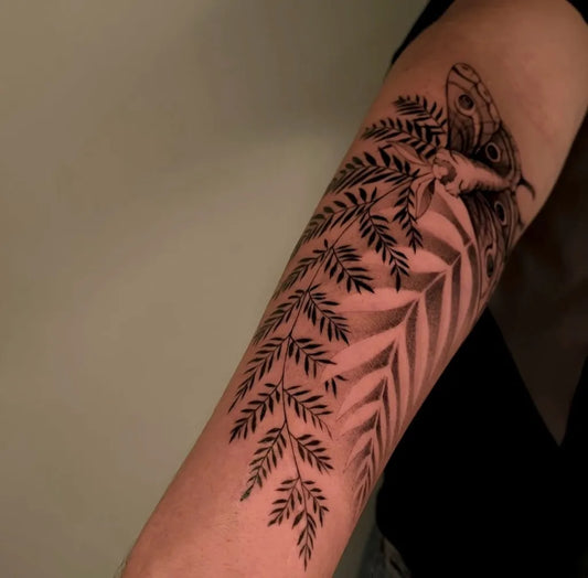 Medium Black and Grey Moth and Ferns Nature Tattoo on Women Arm by @magico.ink