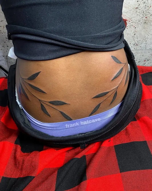 Medium Black and Grey Olive Leaves Tattoo on Women Lower Back by @batcave_tattoos