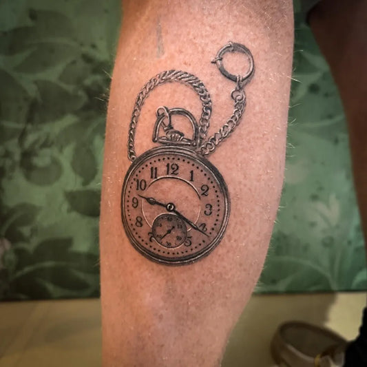 Medium Black and Grey Pocket Watch with Chain Tattoo on Men Leg by @backroomtattoos