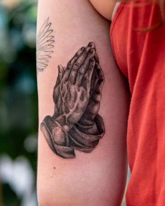 Medium Black and Grey Praying Hands Tattoo on Women Arm by @seventhsontattoo