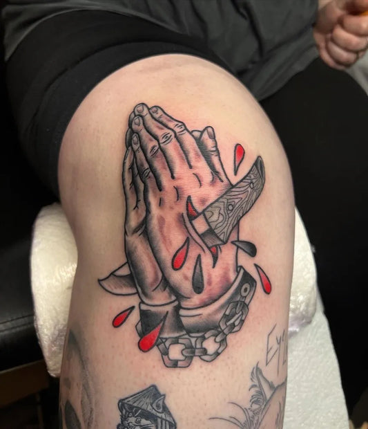 Medium Black and Grey Praying Hands with Dagger and Blood Tattoo on Women Thigh by @hammersmith_tattoo_london