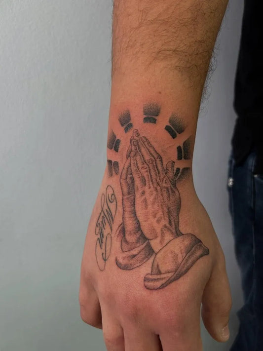 Medium Black and Grey Praying Hands with Halo Tattoo on Men Wrist by @dookies.tattoos