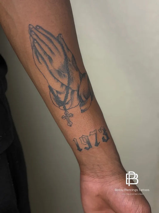 Medium Black and Grey Praying Hands with Rosary and Cross Tattoo on Men Arm by @bossypiercingstattoos