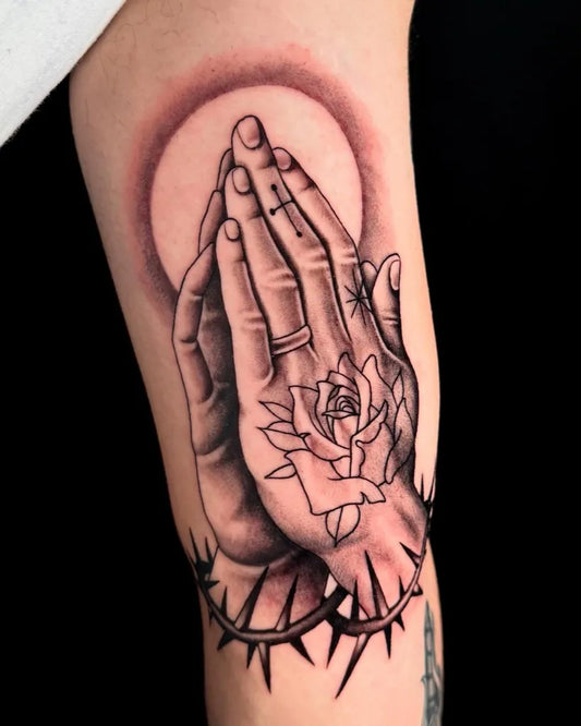 Medium Black and Grey Praying Hands with Rose and Crown of Thorns Tattoo on Men Arm by @annikatattoo