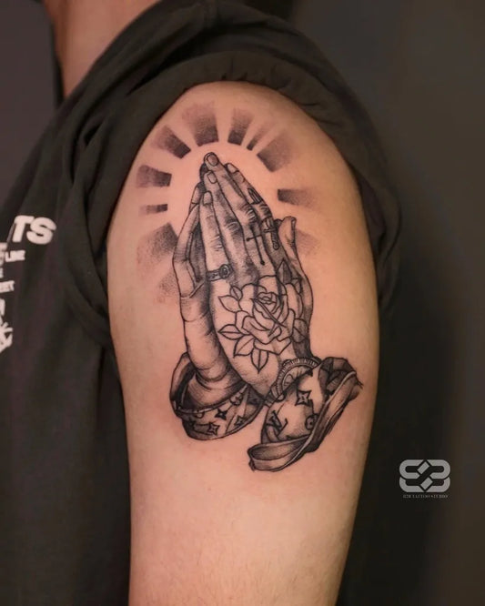 Medium Black and Grey Praying Hands with Rose and Sun Tattoo on Men Upper Arm by @b2btattoo.studio