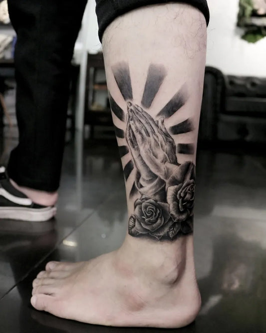 Medium Black and Grey Praying Hands with Roses and Rays Tattoo on Men Leg by @recycle.tattoo