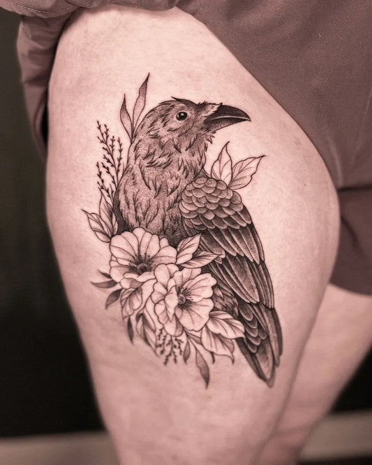 Medium Black and Grey Raven with Flowers on Women Thigh Tattoo by @lucy.inks