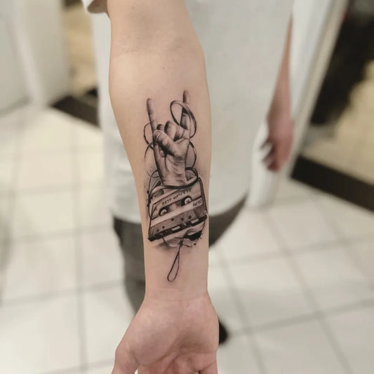Medium Black and Grey Rock Hand Cassette Music Tattoo on Men Arm by @farbecht_bisingen