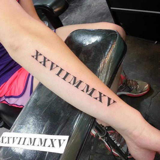 Medium Black and Grey Roman Numerals Tattoo on Women Arm by @dakastattoos