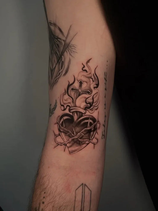 Medium Black and Grey Sacred Heart with Flames and Crown of Thorns Tattoo on Men Arm by @kennz.inki