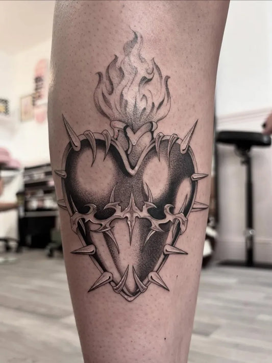 Medium Black and Grey Sacred Heart with Flames and Thorns Tattoo on Women Leg by @kiracartertattoos