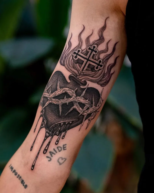 Medium Black and Grey Sacred Heart with Flaming Cross Tattoo on Women Arm by @seventhsontattoo