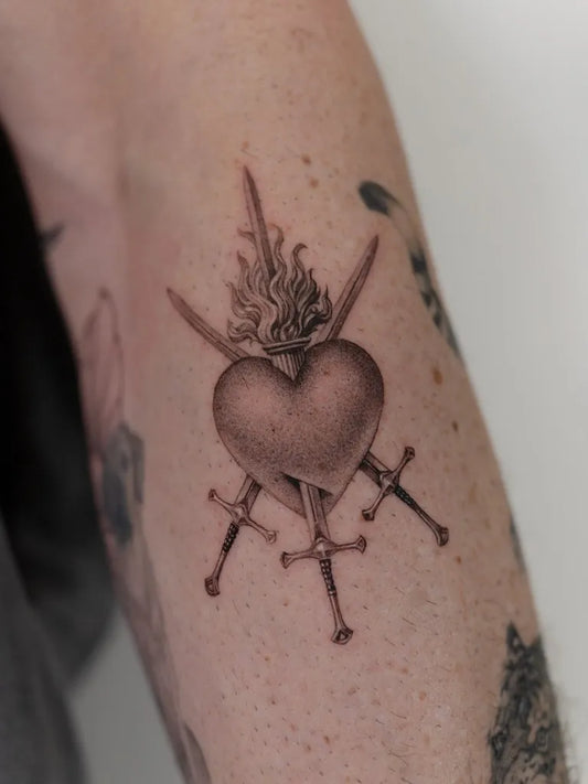 Medium Black and Grey Sacred Heart with Swords and Flames Tattoo on Women Arm by @mumi_ink