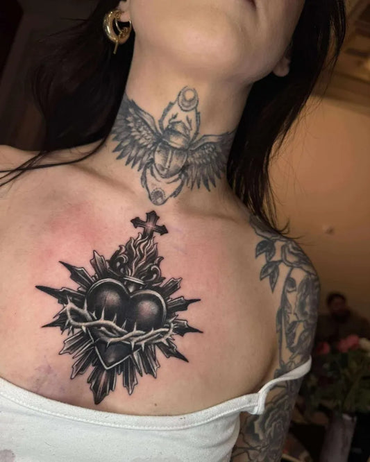 Medium Black and Grey Sacred Heart with Wings and Cross Tattoo on Women Chest by @guerillaartsociety