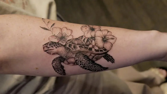 Medium Black and Grey Sea Turtle and Plumeria Tattoo on Women Arm by @rudrainktattoo