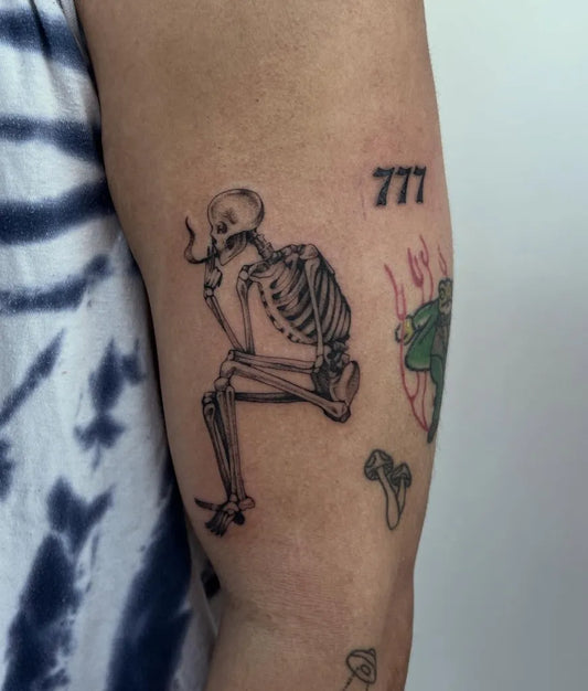 Medium Black and Grey Smoking Skeleton with 777 Tattoo on Men Arm by @4leafbug