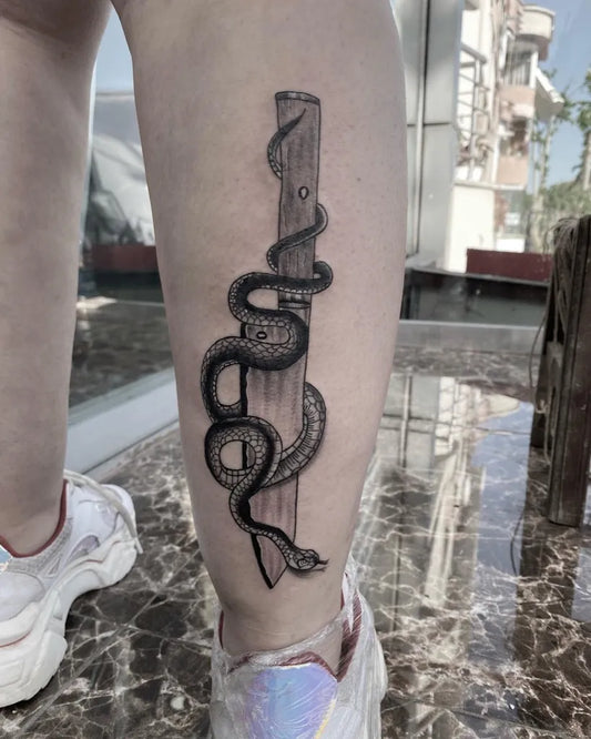Medium Black and Grey Snake Wrapped Knife Tattoo on Women Leg by @wartattoo