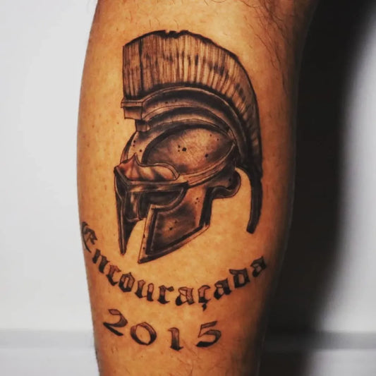 Medium Black and Grey Spartan Helmet with Plume and Date Military Tattoo on Men Leg by @vulcantattoo_pvz