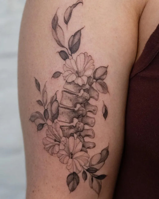 Medium Black and Grey Spine and Flowers Tattoo on Women Upper Arm by @lilyblu.ink