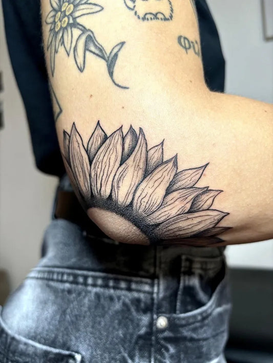 Medium Black and Grey Sunflower on Women Elbow Tattoo by @pepperinflame_tattoo