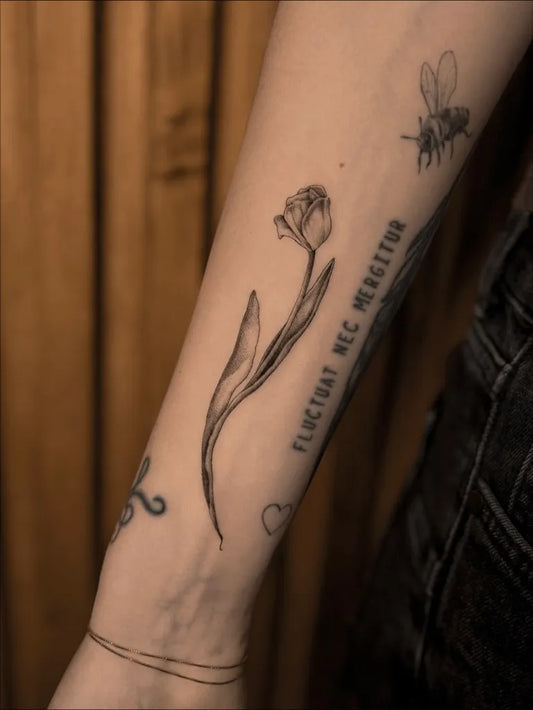 Medium Black and Grey Tulip Bee and Text Tattoo on Women Arm by @copper.tatt