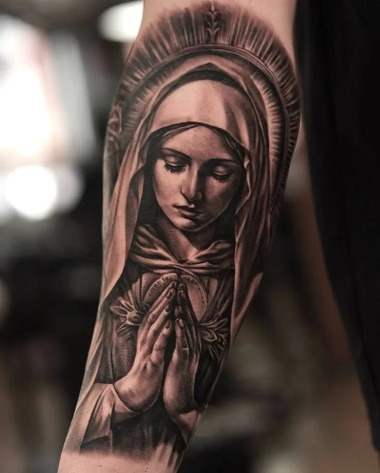 Medium Black and Grey Virgin Mary Praying Tattoo on Women Arm by @lamanigancetattootoronto