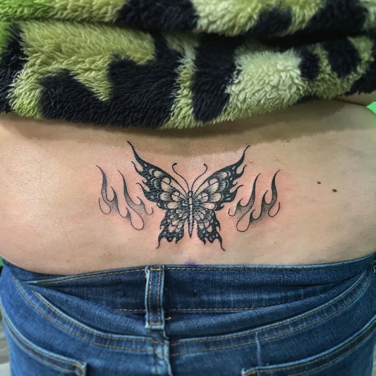 Medium Blackwork Butterfly with Flames Tattoo on Women Lower Back by @el.boi.tattoos