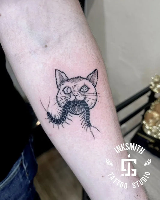 Medium Blackwork Cat Eating Centipede on Women Arm Tattoo by @inksmithtattoobda