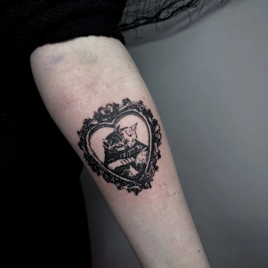 Medium Blackwork Cat in Ornate Heart Frame Tattoo on Women Arm by @cyrk_tattoo