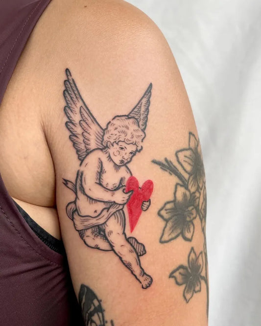 Medium Blackwork Cherub with Heart and Flowers Tattoo on Women Shoulder by @pelc.tt