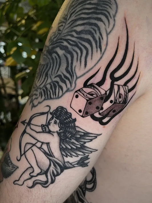 Medium Blackwork Cupid with Dice Tattoo on Men Arm by @joshcoburntattoo