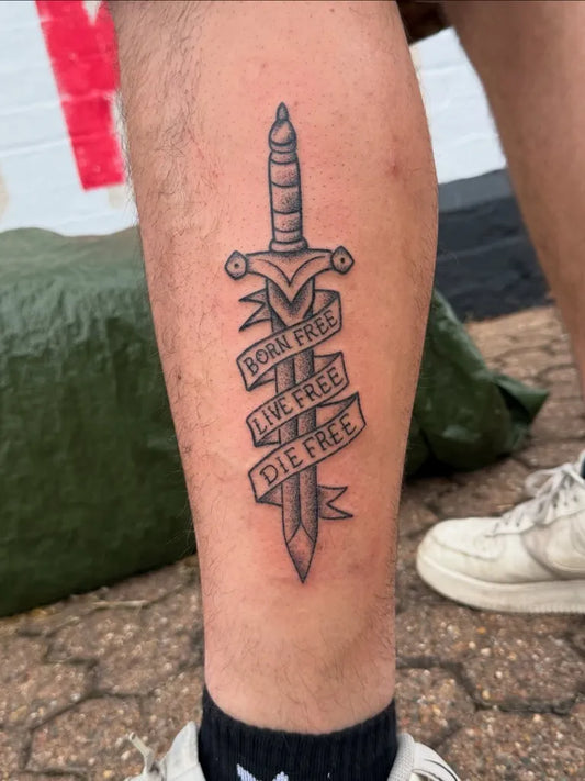 Medium Blackwork Dagger Banner Tattoo on Men Leg by @thefinelinecowboy
