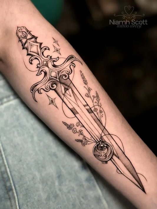 Medium Blackwork Dagger with Floral Elements Tattoo on Women Arm by @niamh_tattoo