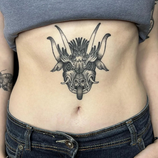 Medium Blackwork Demon Mask Tattoo on Women Stomach by @bassiltattoo