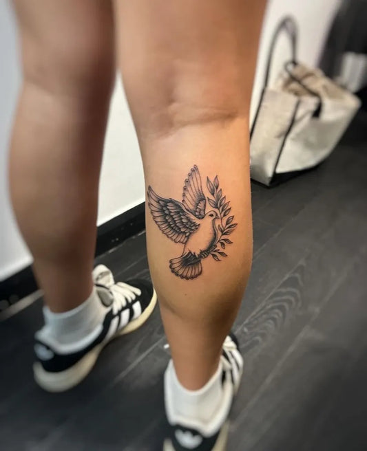 Medium Blackwork Dove with Olive Branch Tattoo on Women Thigh by @ink_angel_tattoo_studio