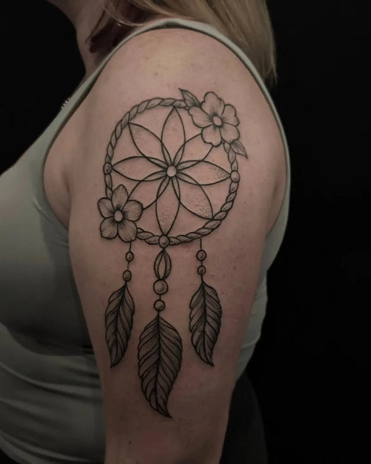 Medium Blackwork Dream Catcher with Flowers and Feathers Tattoo on Women Shoulder by @catus.tattoo